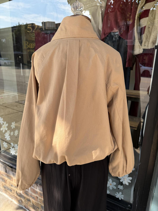 A tan cropped Entro jacket with a high collar and balloon sleeves, shown from the back on a mannequin in a storefront window display.
