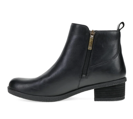 A black leather Dansko Deedee ankle boot with a side zipper, block heel, and pull tab, shown in profile against a white background.