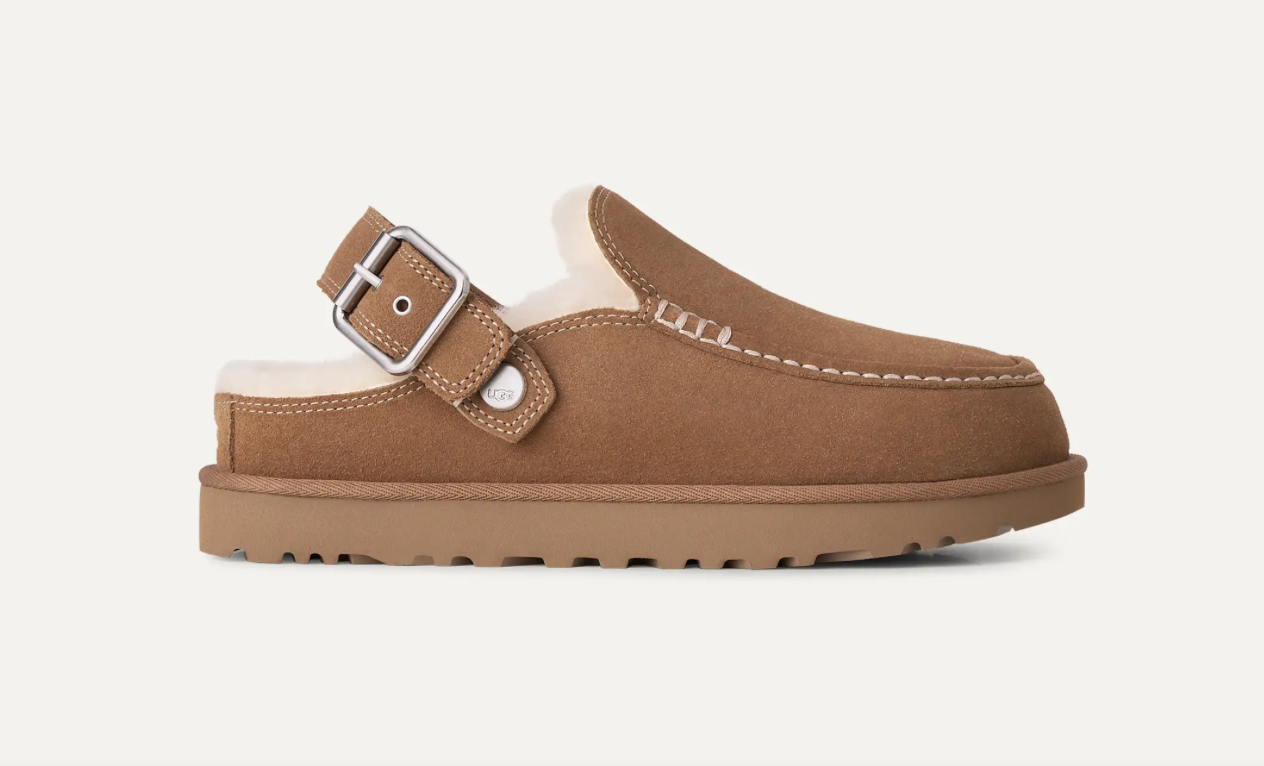 A single brown suede UGG mule clog with a wide adjustable strap and silver buckle, featuring a soft cream shearling lining and a thick brown sole, shown against a plain off-white background.