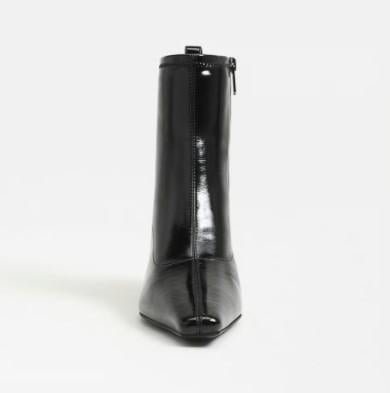 A Circus Inez black patent leather ankle boot with a pointed toe and side zipper, shown from the back on a light gray background.