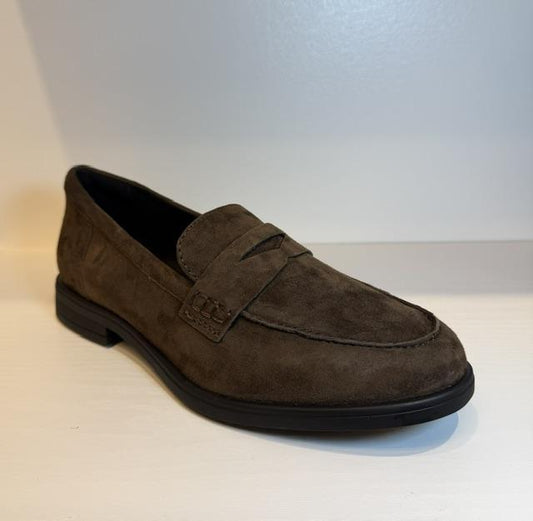 A single Bussola dark brown suede penny loafer shoe with a black sole, photographed on a light-colored surface against a neutral background.