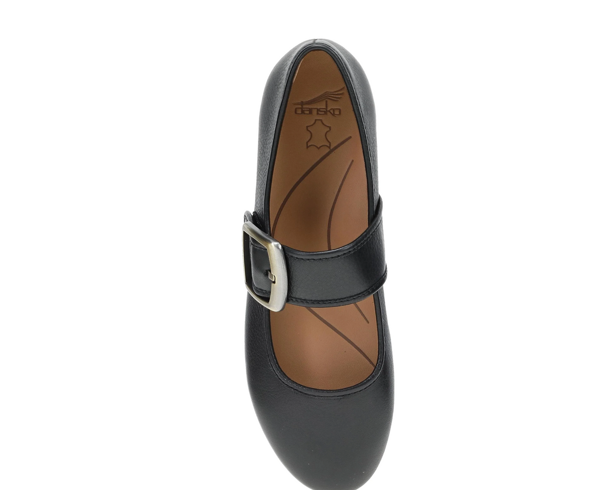 A single Dansko Matilda black leather Mary Jane shoe with a silver buckle strap, shown from a top-down view on a white background. The brand name 'drako' is visible on the tan insole.