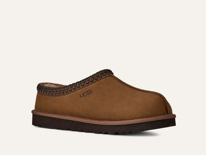 A single UGG Men’s Tasman II Nubuck brown suede slip-on clog shoe with a dark brown braided trim around the opening and a dark brown sole, shown on a light off-white background. The UGG logo is visible on the side.