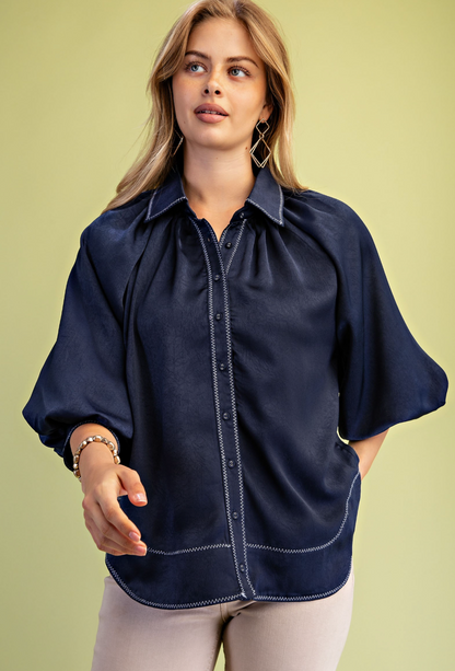 Satin blouse in brown or navy with voluminous balloon sleeves, zig zag stitching and a smooth draped silhouette.