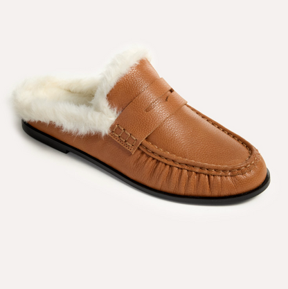 A tan Yosi Samra Camden slip-on loafer with a white faux-fur lining, shown from a three-quarters angle on a light off-white background.
