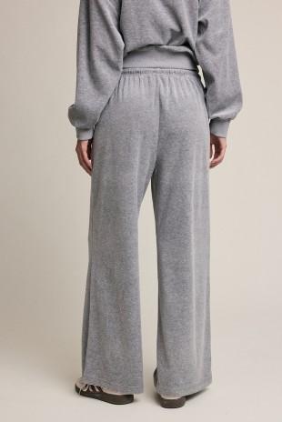 A person shown from the back wearing heather gray wide-leg sweatpants and a matching gray sweatshirt against a plain light beige studio background.