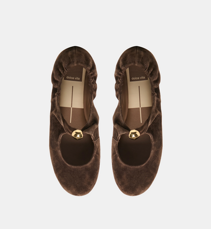 A pair of dark brown Dolce Vita Cornel suede Mary Jane flats with gold-tone metal accents, shown from a top-down view on a light gray background.