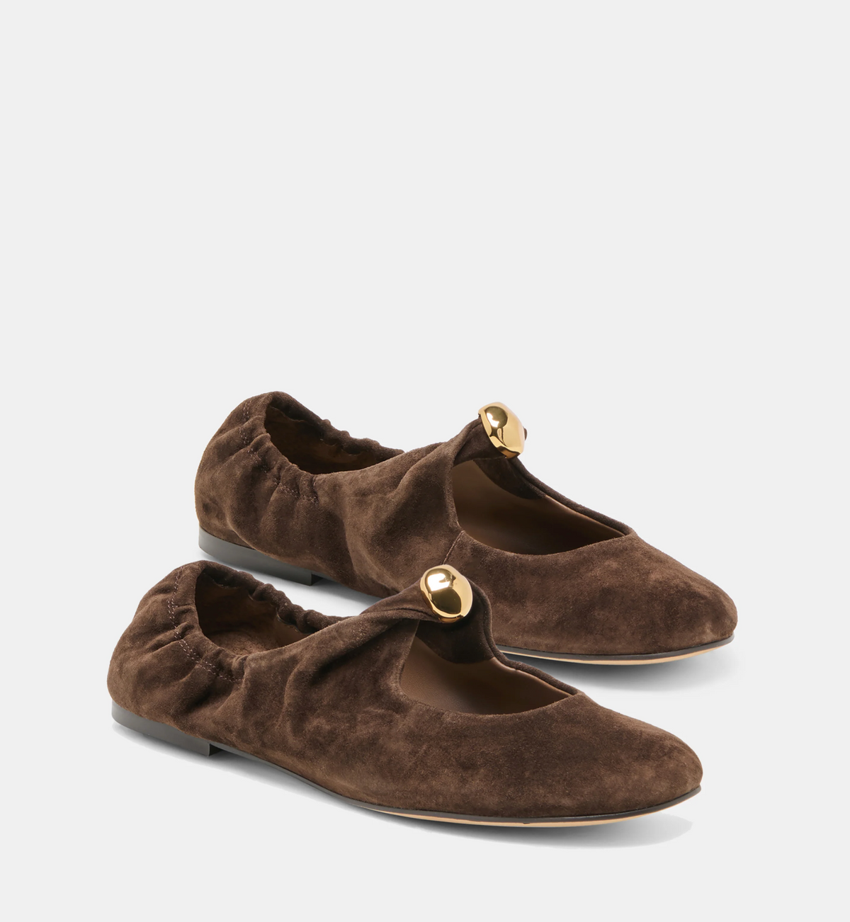 A pair of dark brown Dolce Vita Cornel suede ballet flats with a small gold-tone circular metal accent on the strap, photographed on a clean light gray studio background.