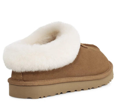 A tan suede slipper with a thick white shearling-style collar and a tan rubber sole, shown from a side-rear angle on a white background.
