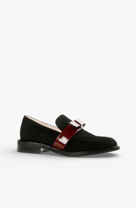 A single black suede Mary Jane loafer with a glossy burgundy patent leather strap and a silver-tone metal buckle, shown from a side profile on a light gray background.