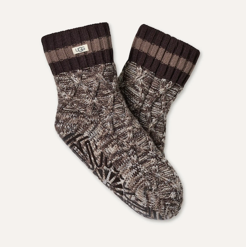 A pair of UGG ankle socks in a dark brown and gray cable-knit pattern, featuring a ribbed cuff with horizontal brown stripes and a small white UGG logo tag.