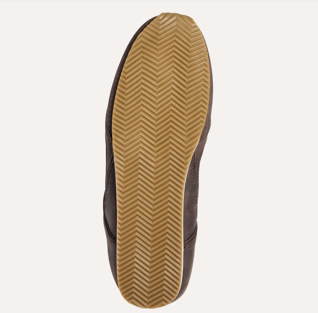 A top-down view of a shoe's sole, showing a Yosi Samra dark brown suede upper and a tan rubber outsole with a herringbone tread pattern, set against a plain off-white background.