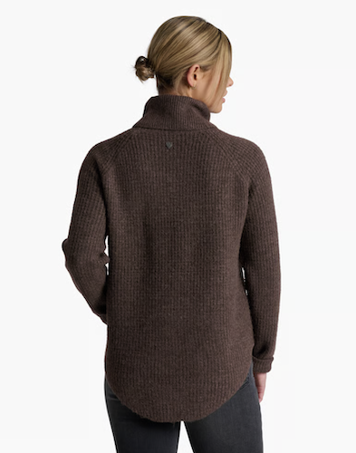 A woman shown from the back wearing a dark brown Kuhl Sienna ribbed knit turtleneck sweater and dark jeans against a plain white studio background.