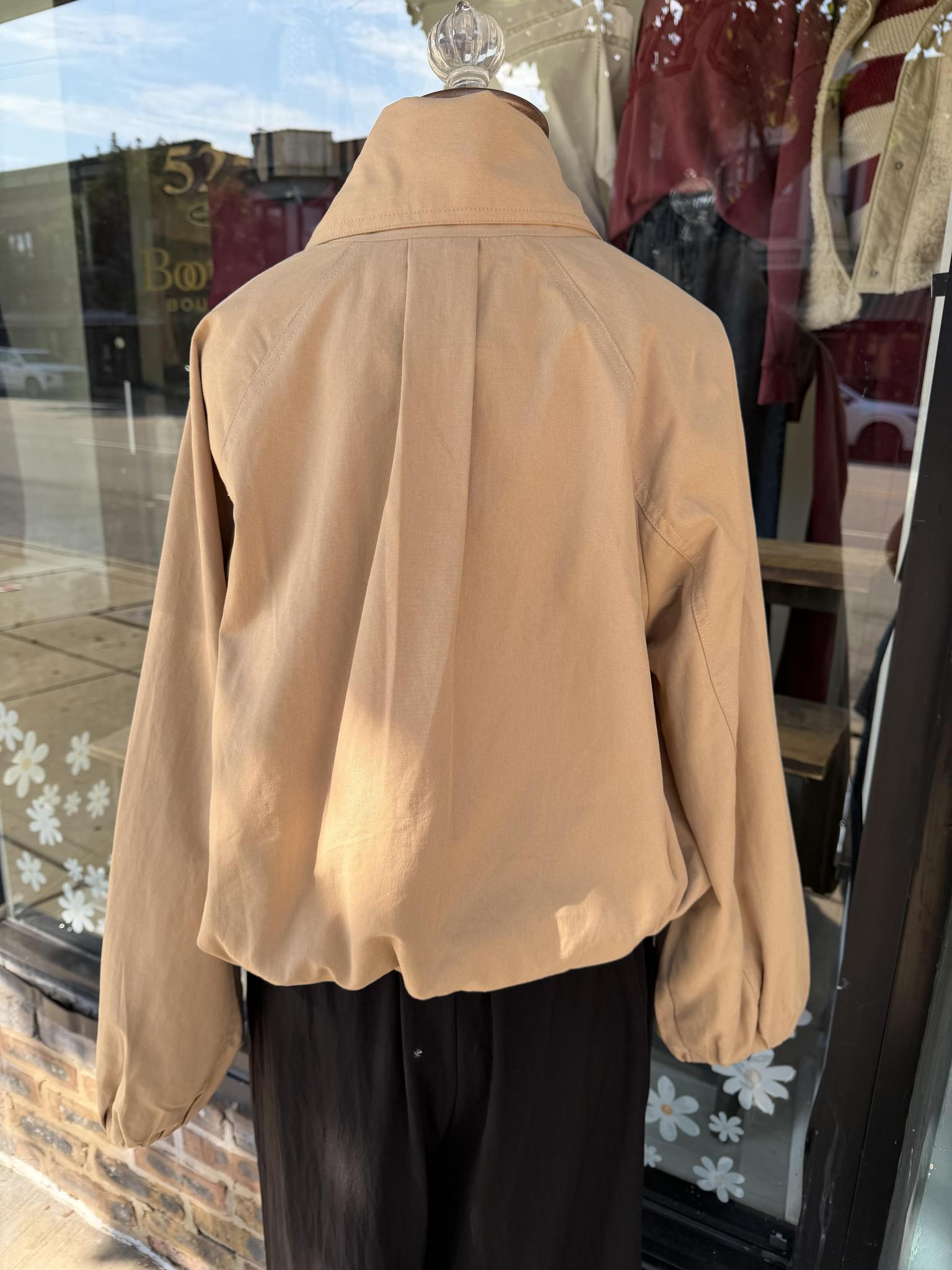 A tan cropped Entro jacket with a high collar and balloon sleeves, shown from the back on a mannequin in a storefront window display.