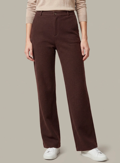A model wearing dark brown 525 America straight-leg trousers, a beige long-sleeve top, and white sneakers, shown from the waist down against a solid light gray background.