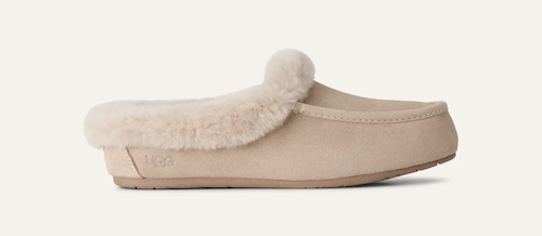 A single beige UGG Ansley slip-on mule shoe with fluffy cream shearling lining and a pom-pom detail on the vamp, shown in profile against a light off-white background.