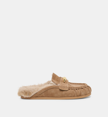 A single Dolce Vita Jodero tan suede slip-on flat with a soft cream faux-fur lining and a small gold-tone decorative accent on the strap, shown in side profile against a plain light gray background.