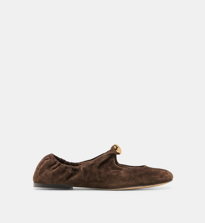 A single brown Dolce Vita Cornel suede flat shoe with a gathered elastic top and a small gold metal accent on the toe, shown against a plain light gray background.