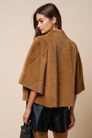Woman wearing a brown poncho against a beige background