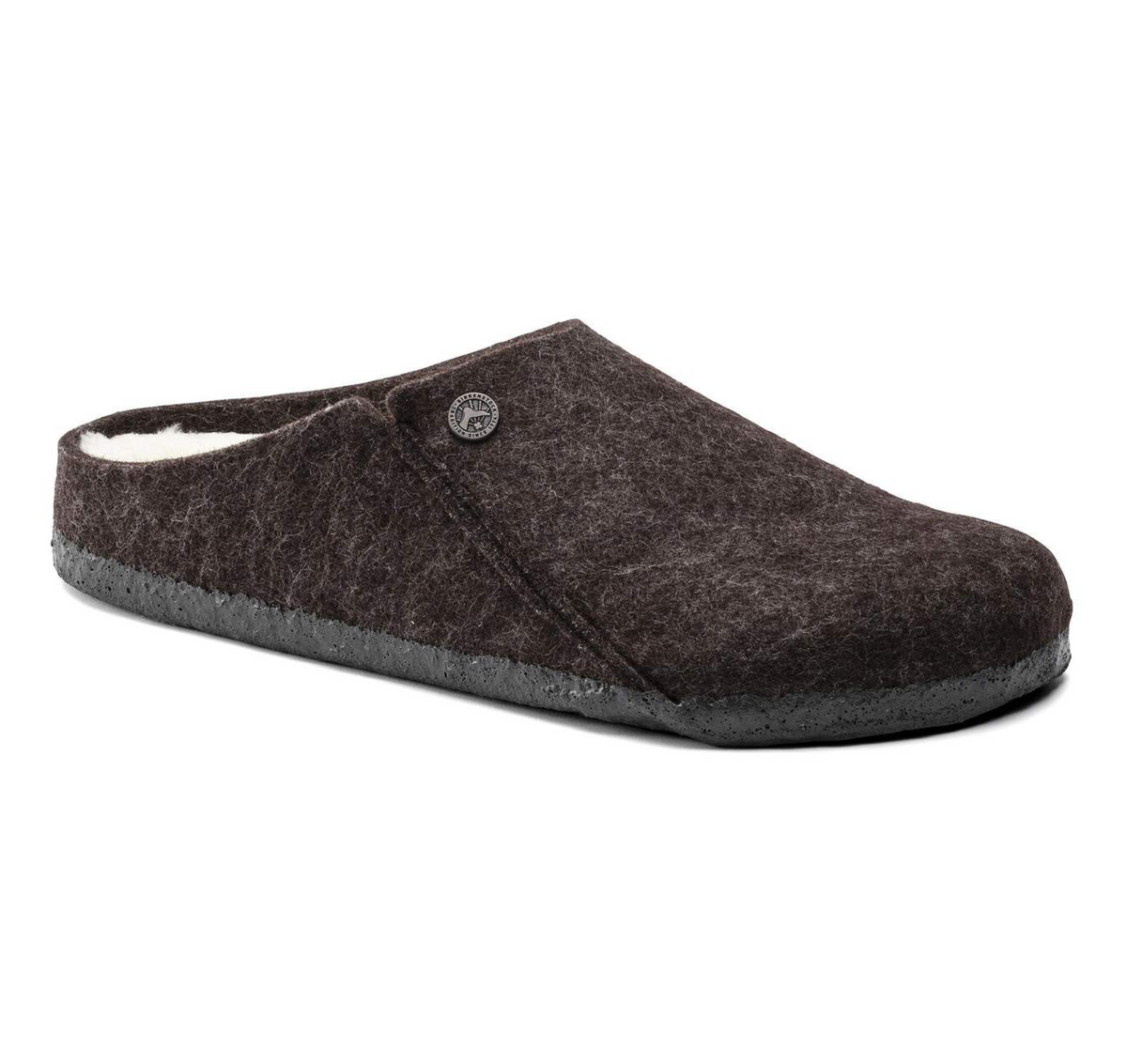 A dark brown felt slip-on  Birkenstock Zermatt Shearling clog shoe with a soft white lining visible at the opening and a small round metal logo button on the side, set against a plain white background.