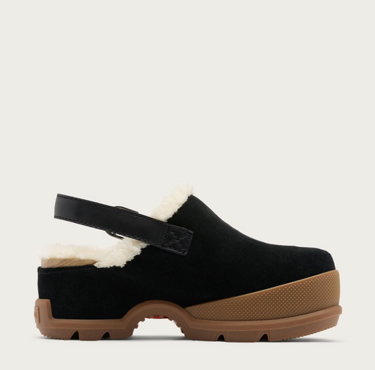 A Sorel black suede clog shoe with a white shearling lining, a black adjustable strap, and a brown textured sole, shown from a side profile on a light beige background.