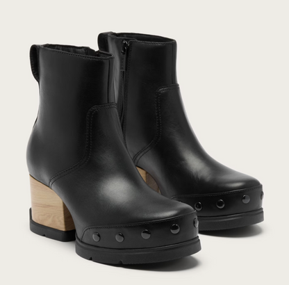 A pair of Sorel waterproof black leather ankle boots with chunky light wood block heels, black platform soles with metal studs, and side zippers, shown on a light gray background.