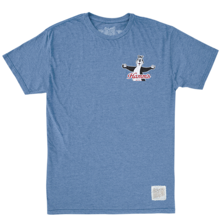 A heather blue short-sleeve t-shirt with a small graphic on the left chest featuring a cartoon bear and the text 'Hamm's Beer'. A small white woven label is visible near the bottom right hem.