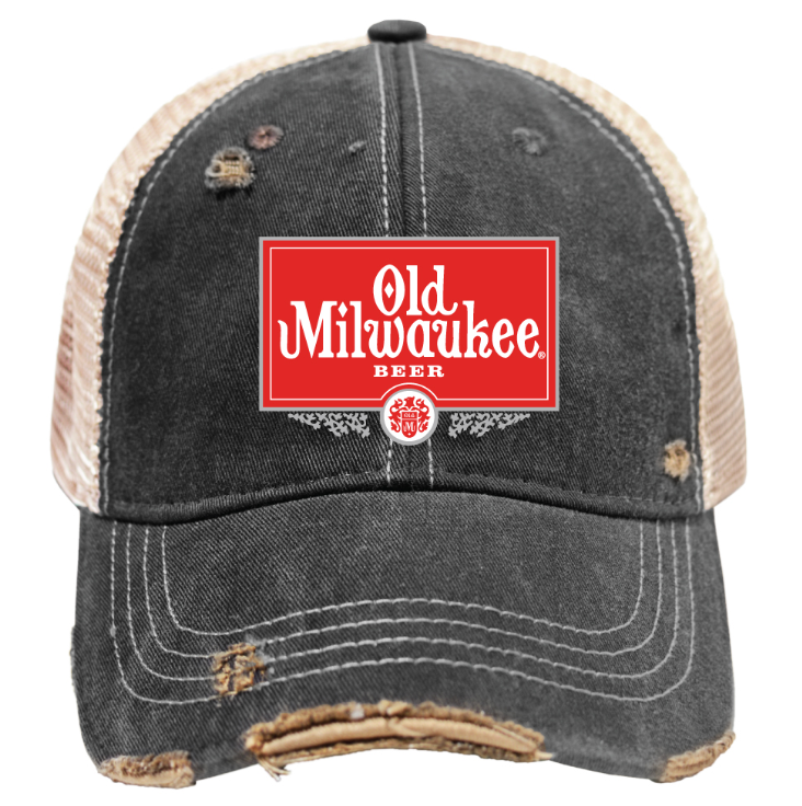 A distressed trucker-style baseball cap with a dark gray washed front panel and brim, beige mesh back panels, and a prominent red rectangular Old Milwaukee Beer logo patch on the front.