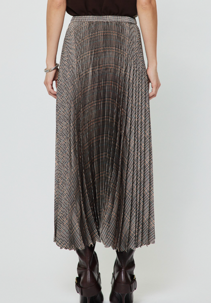 A Current Air pleated midi skirt with a brown, beige, and black plaid pattern, worn by a model with dark brown ankle boots against a light gray studio background.