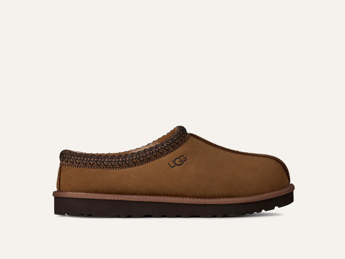 A single UGG Men’s Tasman II Nubuck brown suede UGG slip-on clog shoe with a dark brown braided trim and a dark brown sole, shown from a side profile on a light off-white background.