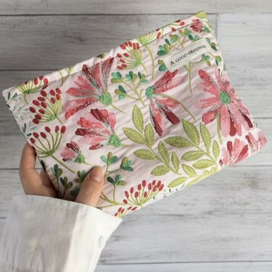 Beige cosmetic bag with pink and green botanical floral print and zip‑top closure.