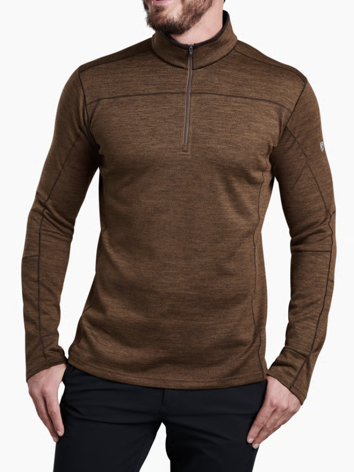 A man wearing a Kuhl Ryzer brown heathered quarter-zip long-sleeve athletic shirt, paired with black pants, against a plain white background.
