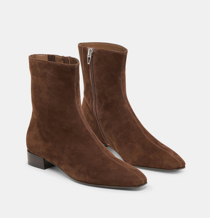 A pair of Dolce Vita Tarine brown suede ankle boots with pointed toes and low block heels, shown from the side on a light gray background.