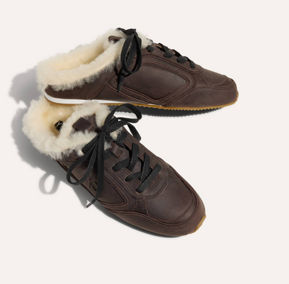 A pair of Yosi Samra dark brown leather slip-on sneakers with thick cream shearling lining and black laces, displayed on a clean off-white background.