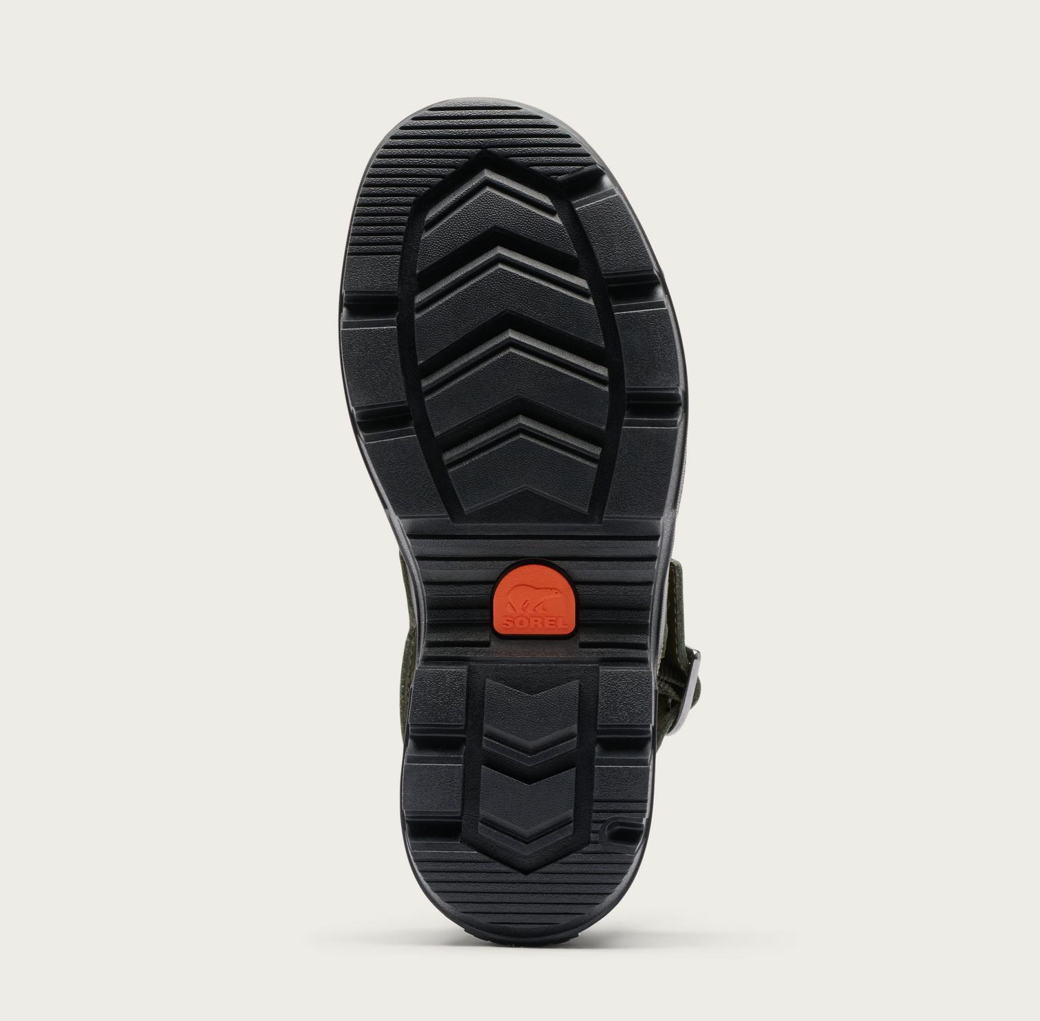 The black rubber outsole of a Sorel Roam’n Clog, shown from a top-down view against a light beige background. The sole features a deep chevron tread pattern and a small, bright orange circular brand patch in the center.