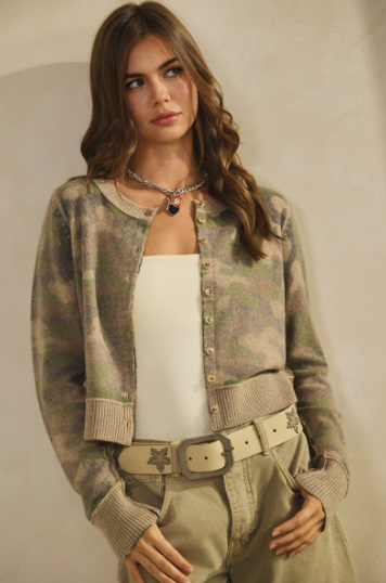 A woman modeling a lightweight camo cardigan with relaxed open‑front fit and soft drape, worn over a white top and paired with khaki pants and a belt.