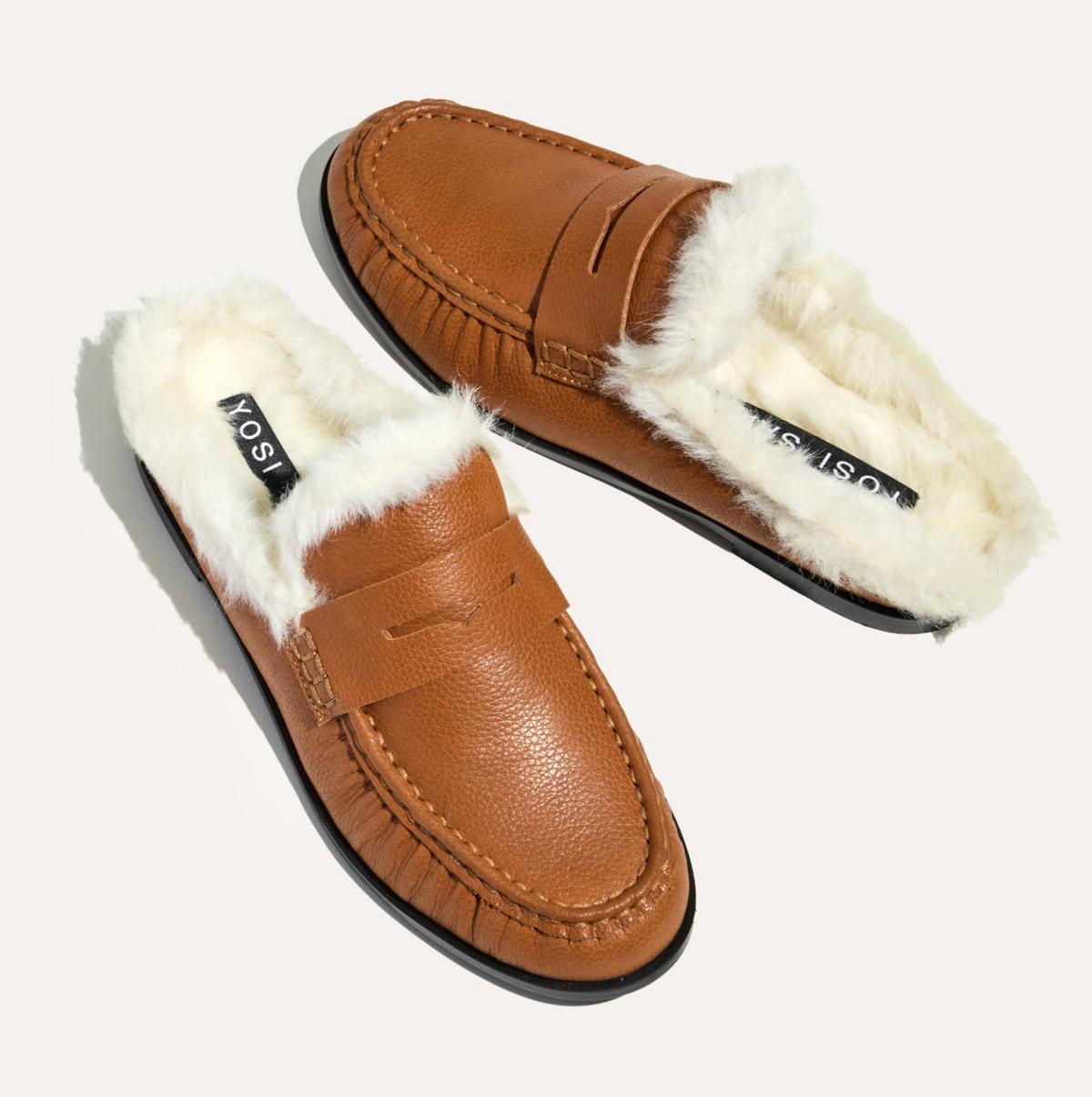 A pair of tan Yosi Samra Camden leather slip-on loafers with fluffy white shearling lining, displayed on a light cream background.