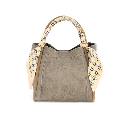 A structured handbag in taupe suede with tan leather trim and a beige silk scarf with a black geometric pattern tied around the top handle, shown on a plain white background.