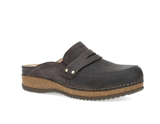 A Dansko dark brown suede clog shoe with a wide strap across the top, secured by two silver metal rivets, and a thick textured cork wedge heel, shown from a side profile on a white background.
