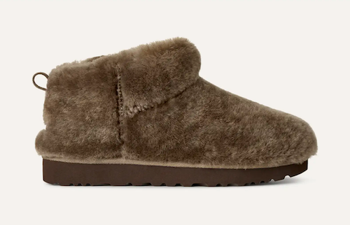 A single UGG Classic Ultra Mini shearling slipper boot in taupe-brown, featuring a soft, fuzzy shearling upper and a dark brown sole, shown from a side profile against a light off-white background.
