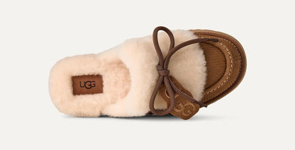 A single UGG Disquette Heritage slipper in a side profile view, featuring a soft cream-colored shearling upper, a brown leather sole, and a matching brown leather bow with a UGG logo charm, set against a light off-white background.