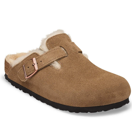 A tan suede Birkenstock clog with a soft cream shearling lining and a rose gold buckle strap, shown from a three-quarter angle on a white background.