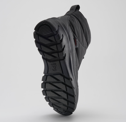 A Kamik Snowdon black mid-height winter boot shown from a rear three-quarter angle, highlighting its rugged treaded sole and quilted upper against a light gray studio background.