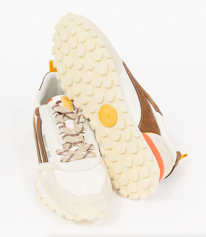 A pair of low-top Oncept sneakers shown on a clean white background, with one shoe standing upright and the other lying on its side to display the sole. The shoes feature a cream and white leather and suede upper with brown side panels, patterned laces, and a yellow circular logo on the sole.