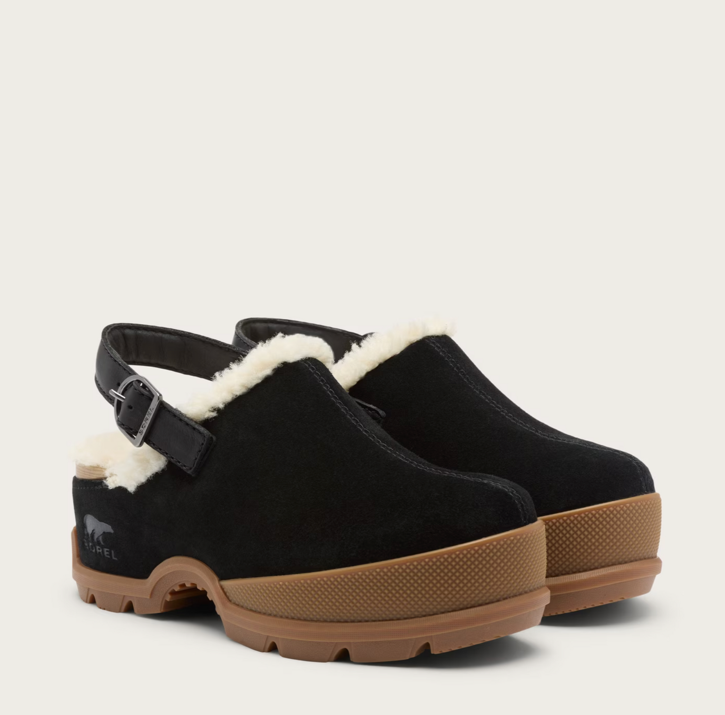A pair of Sorel black suede clogs with white shearling lining, black ankle straps, and brown rubber soles, shown on a light beige background.