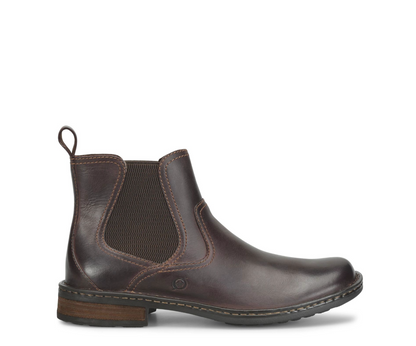 A dark brown leather Chelsea boot with a dark brown elastic side panel, a pull loop at the back collar, and a low stacked heel, shown in profile against a white background.