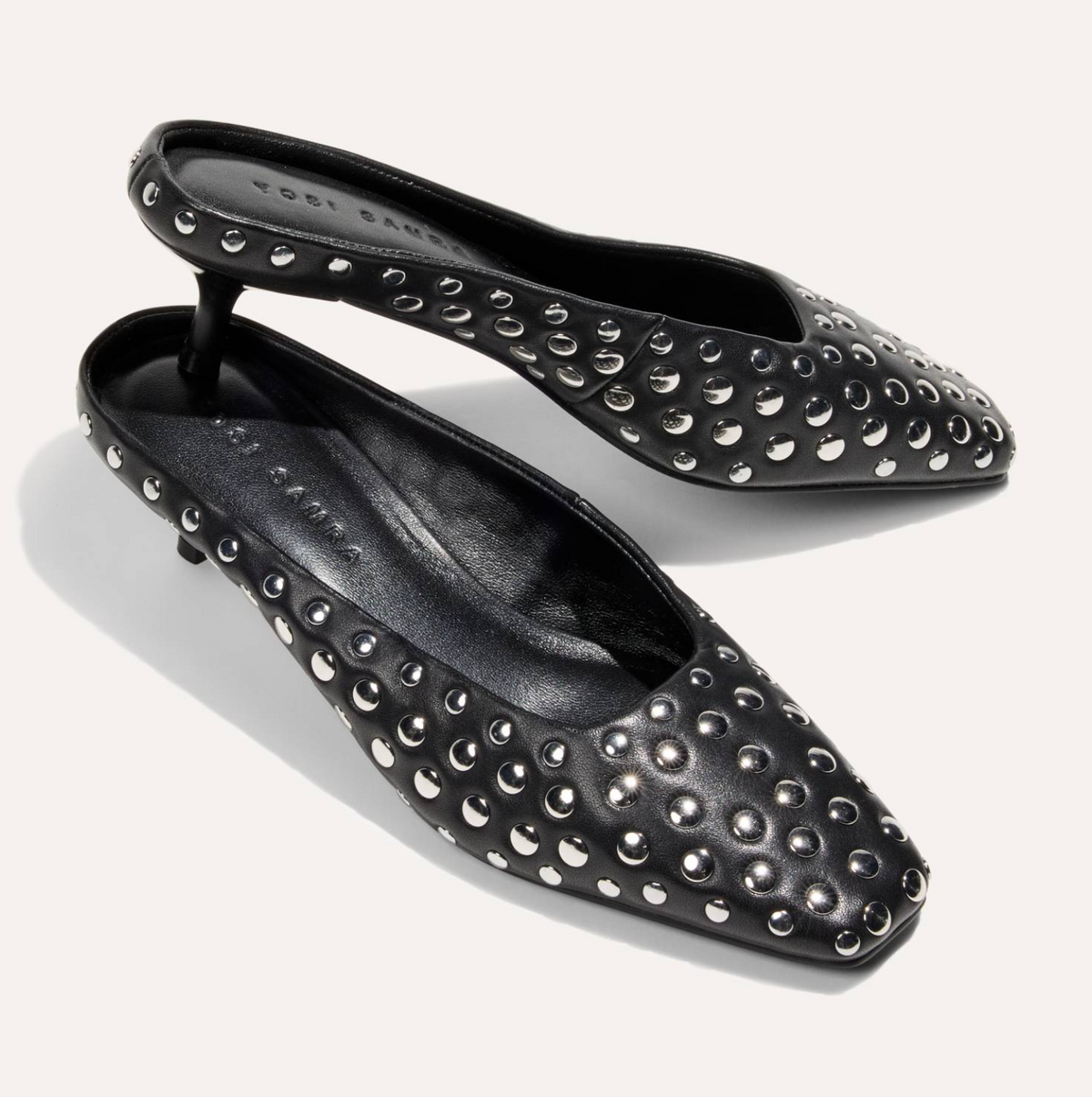 A pair of black pointed-toe flats by Yosi Samra, embellished with silver-tone metal studs, shown on a light off-white background.