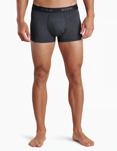 A man wearing dark gray heathered boxer briefs with a black waistband featuring the KÜHL brand name in white, shown from the waist down on a light gray studio background.
