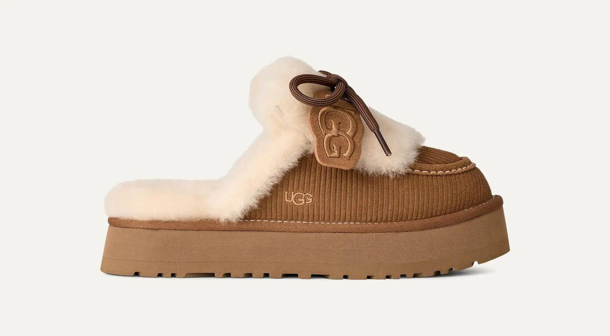 A single UGG Disquette Heritage mule slipper in brown corduroy with a cream shearling lining and a brown leather logo charm, shown against a light off-white background.