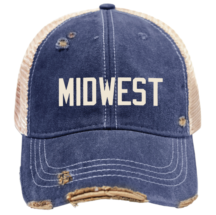 A distressed trucker-style baseball cap with a blue denim front and brim, beige mesh back panels, and the word 'MIDWEST' embroidered in white across the front. The cap has intentional rips and frayed detailing around the brim and eyelets.